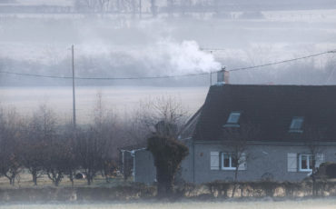 Kaldt hus på jorde med røyk fra pipe og frostrøyk på bakken